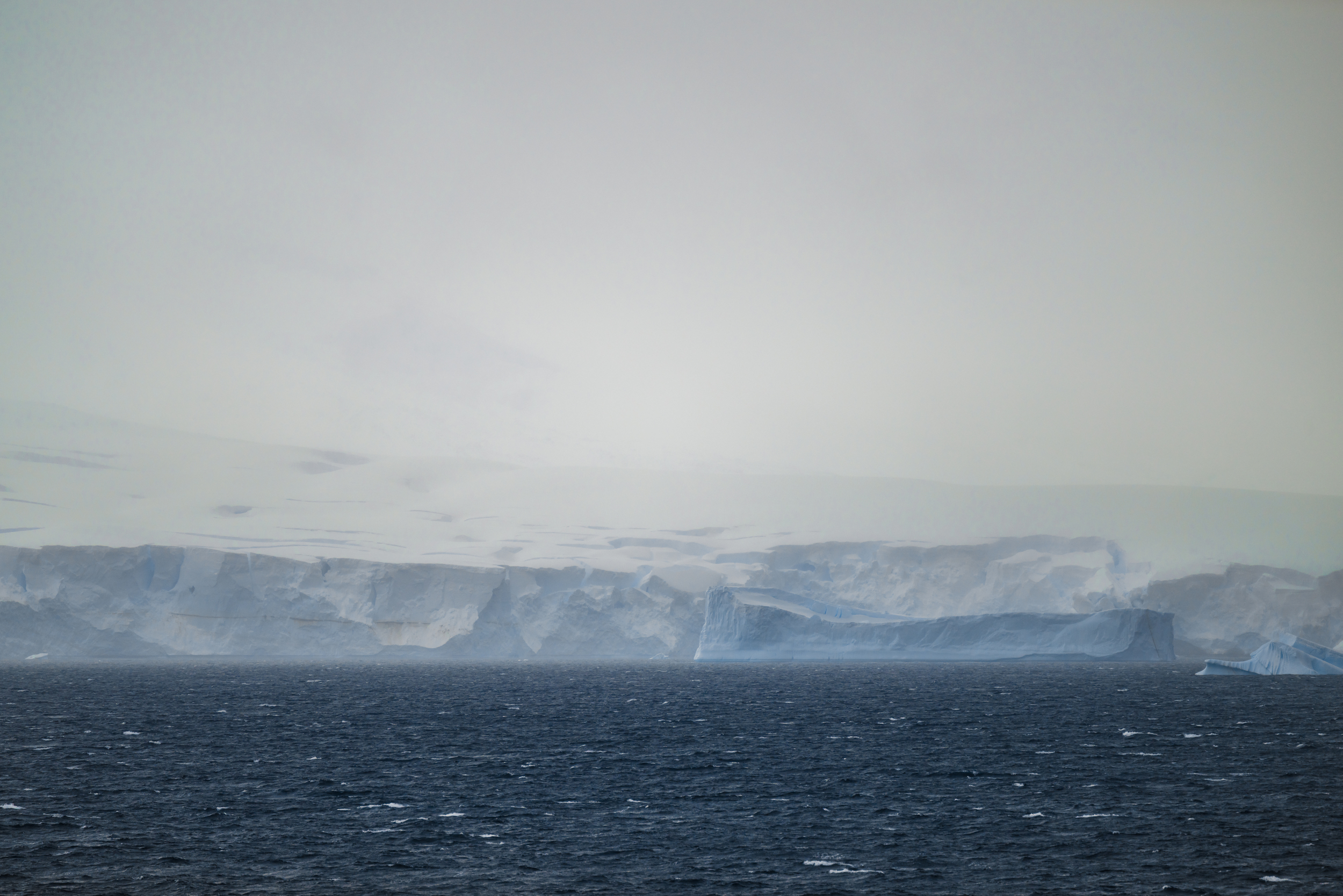 The Antarctic ice frontier, tabular icebergs across a dark southern sea