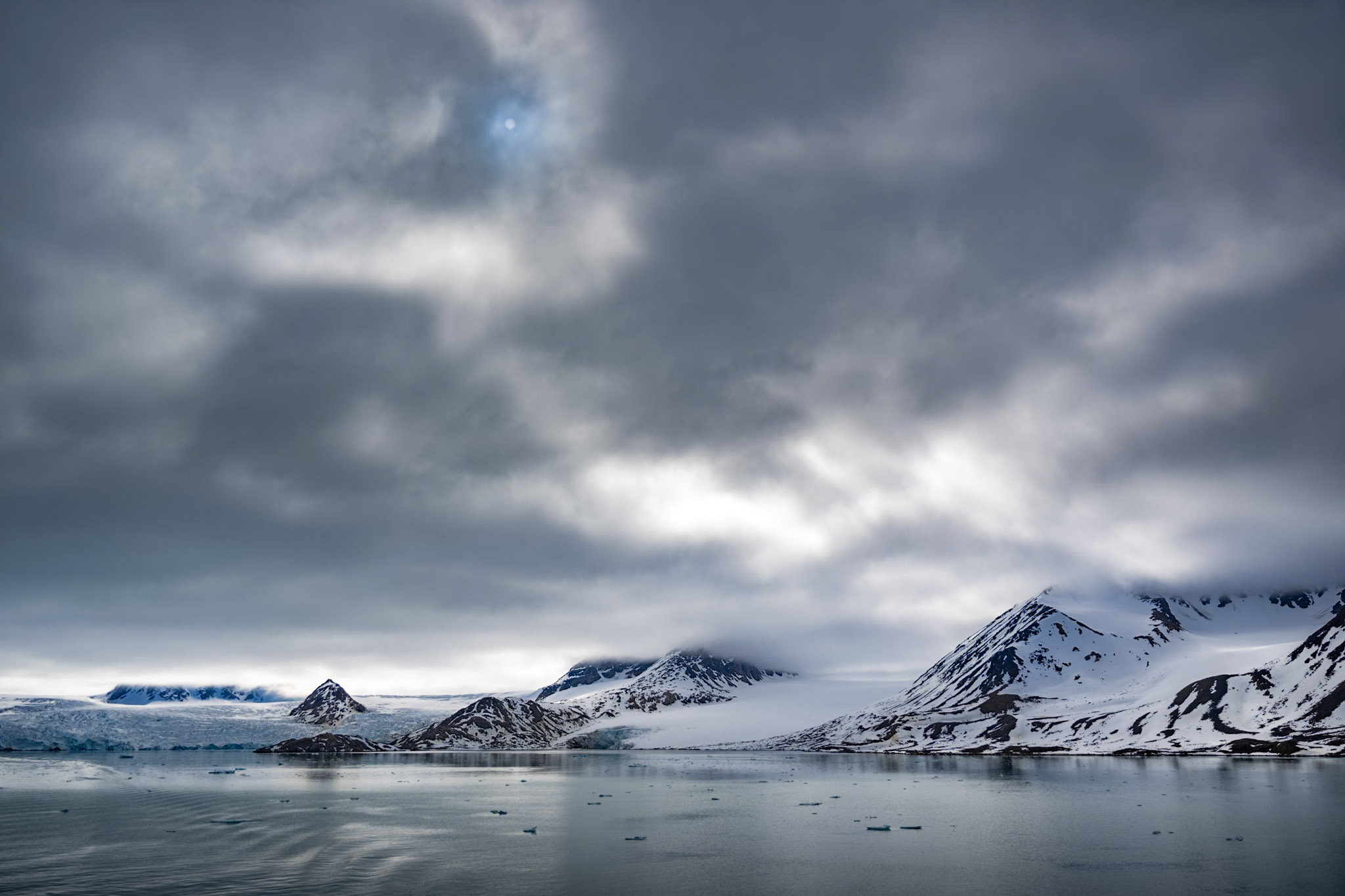 Snow-clad peaks above a still Arctic fjord