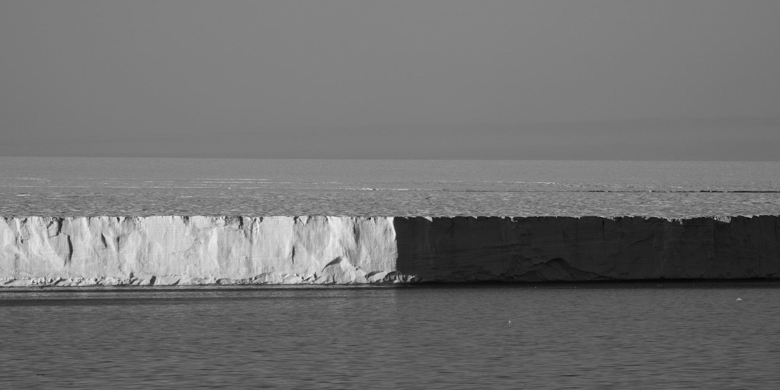 The face of an ice shelf meeting the Arctic sea